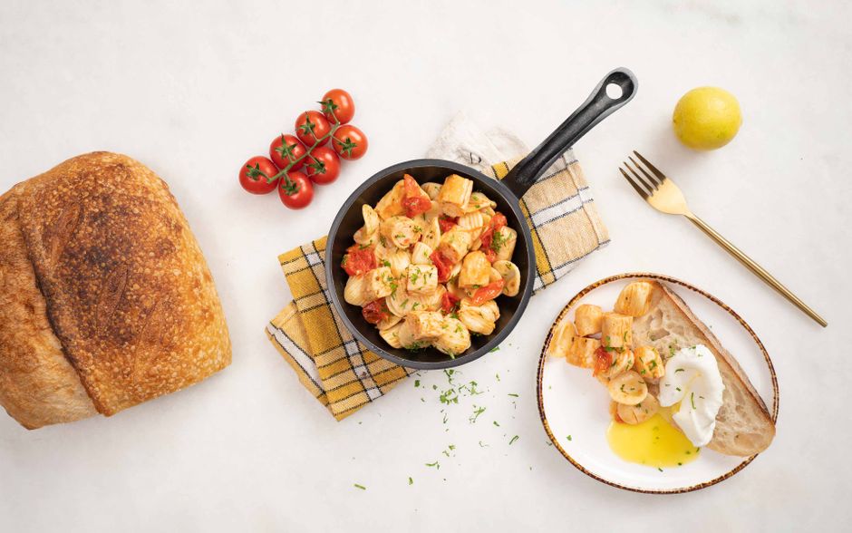 Delicious Italian pasta in a skillet with fresh ingredients and rustic bread.